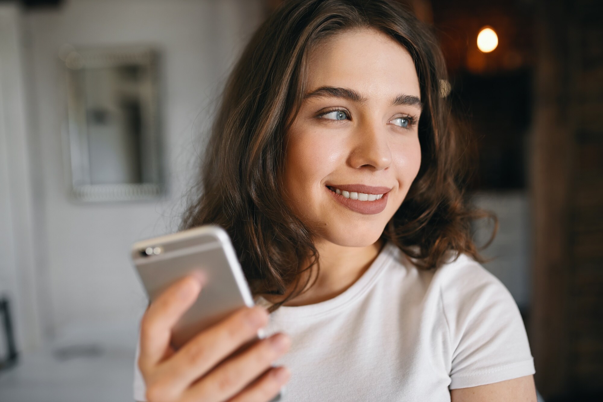 Jeune femme souriante qui lit un message sur son téléphone